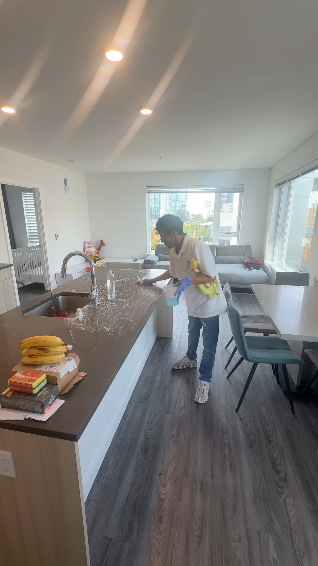 Cenlora cleaner cleaning a kitchen island in a bright open-plan home